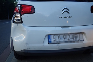 na zdjęciu fragment białego samochódu z uszkodzonym lewym reflektorem