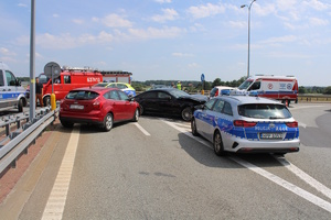 na zdjęciu miejsce kolizji dwóch samochodów, obok nich radiowozy i wozy strażackie