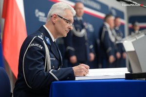 na zdjęciu komendant wojewódzki w trakcie wpisywania się do księgi