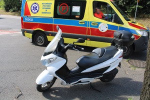 na zdjęciu biały motocykl, za nim karetka pogotowia