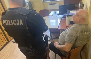 na zdjęciu policjant przy zatrzymanym, który siedzi na krześle