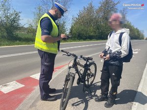 na zdjęciu policjant na drodze rowerowej, obok niego rowerzysta i rower