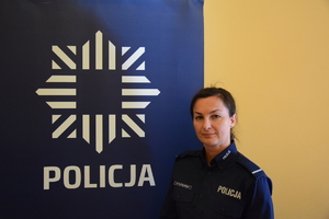 na zdjęciu dzielnicowa Piotrowska przy banerze z napisem policja