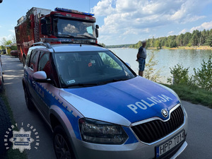 na zdjęciu radiowóz nad zalewem, za nim wóz strażacki