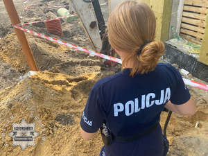 na zdjęciu policjantka przy górce ziemi, na której widoczny granat