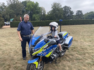 na zdjęciu dziecko na policyjny motocyklu, obok policjant