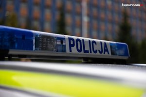 na zdjęciu policyjny neon na dachu radiowozu, w tle widoczny budynek komendy