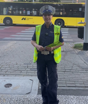 na zdjęciu policjantka z odblaskami w rękach, za nią przejście dla pieszych