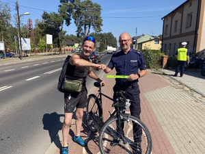 na zdjęciu policjant z rowerzystą w trakcie przybijania tak zwanego &quot;żółwika&quot; na drodze rowerowej