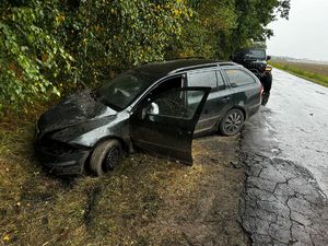 na zdjęciu czarny samochód osobowy z rozbitym przodem w rowie