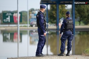 na zdjęciu policjanci przy zalanej drodze