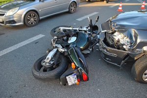 na zdjęciu samochodów osobowy z rozbitym przodem, a przed nim leżący uszkodzony motocykl