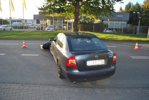 na zdjęciu samochodów osobowy z rozbitym przodem, a przed nim leżący uszkodzony motocykl, przed nimi budynek i inne pojazdy