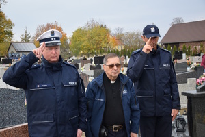 na zdjęciu policjanci oddający honor nad grobem, pomiędzy nimi kapela Policji