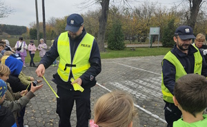 na zdjęciu policjanci rozdający odblaski dzieciom