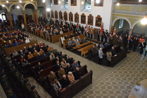 na zdjęciu widok na kościół, gdzie w ławkach wierni, obok poczty sztandarowe