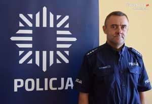 na zdjęciu dzielnicowy Michalik przy banerze z napisem policja