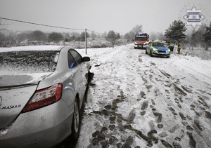 na zdjęciu tył srebrnego samochodu, przed nim radiowóz i wóz strażacki ze strażakami na zaśnieżonej jezdni