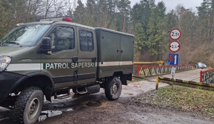 na zdjęciu wóz patrolu saperskiego przed mostem, za mostem radiowóz policyjny