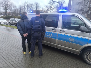 na zdjęciu policjant przy radiowozie z zatrzymanym mężczyzną