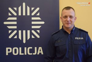 na zdjęciu dzielnicowy Cieślik przy banerze z napisem policja