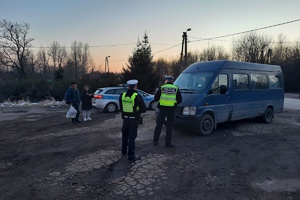 na zdjęciu policjanci, przed nimi bus, radiowóz i dwie osoby