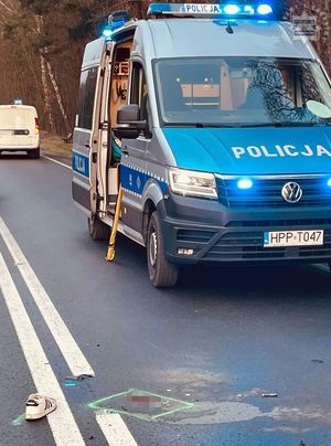 na zdjęciu radiowóz policyjny na sygnałach błyskowych, obok na jezdni ślady po zdarzeniu i leżący but
