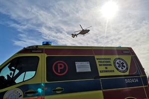 na zdjęciu karetka pogotowia, a nad nią śmigłowiec lotniczego pogotowia ratunkowego