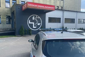 na zdjęciu fragment radiowozu zaparkowany przed szpitalnym oddziałem ratunkowym