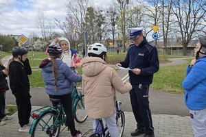 na zdjęciu policjant i rowerzyści w miasteczku ruchu drogowego