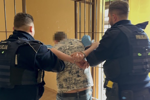 na zdjęciu policjanci wprowadzający zatrzymanego do celi