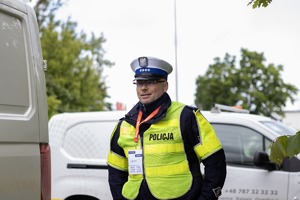 na zdjęciu policjant w kamizelce i samochody