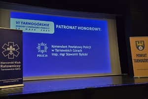 na zdjęciu scena, gdzie na ekranie wyświetlony napis patronat honorowy komendant powiatowy policji w tarnowskich górach inspektor magister Sławomir Bylicki