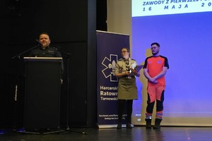 na zdjęciu komendant byliski na scenie przy mównicy, obok osoby