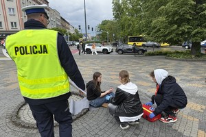 na zdjęciu policjant, a przed nim na ziemi osoby w trakcie pozorowanej scenki ratunkowej