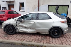na zdjęciu samochód zaparkowany na chodniku z widocznymi uszkodzeniami