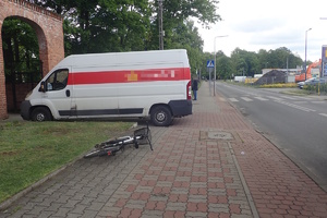 na zdjęciu dostawczy samochód zaparkowany na chodniku, obok leżący na chodniku rower