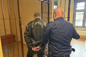 na zdjęciu policjant z zatrzymanym mężczyzną