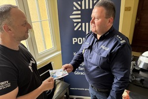 na zdjęciu komendant Bylicki wręcza ulotkę mężczyźnie