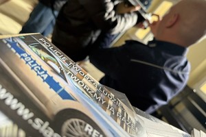 na zdjęciu fragment ulotki policyjnej i w oddali policjant
