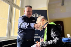 na zdjęciu komendant Bylicki zawiesza na szyi dziecka pamiątkową smycz