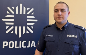 na zdjęciu dzielnicowy Bissinger przy banerze z napisem policja