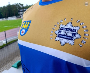 na zdjęciu fragment koszulki, na którym herb powiatu i logo policji