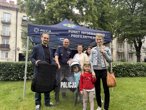 na zdjęciu policjant z osobami przed policyjnym namiotem