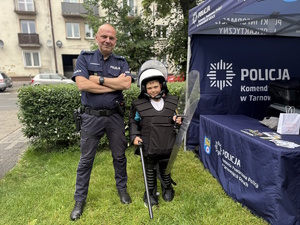 na zdjęciu policjant z dzieckiem przy namiocie policyjnym