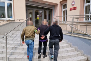 na zdjęciu policjanci po cywilu prowadzą zatrzymanego do budynku prokuratury