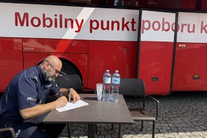 na zdjęciu komendant przy stoliku obok autokaru