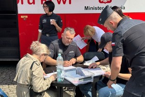 na zdjęciu osoby obok autokaru przy stoliku