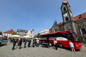 na zdjęciu rynek i autokar do poboru krwi oraz osoby przy nim