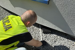 na zdjęciu policjant przy czarnej paczce